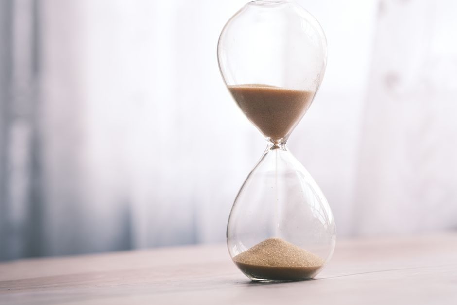 Minimalist hourglass filled with sand symbolizing time and patience, against a soft background.